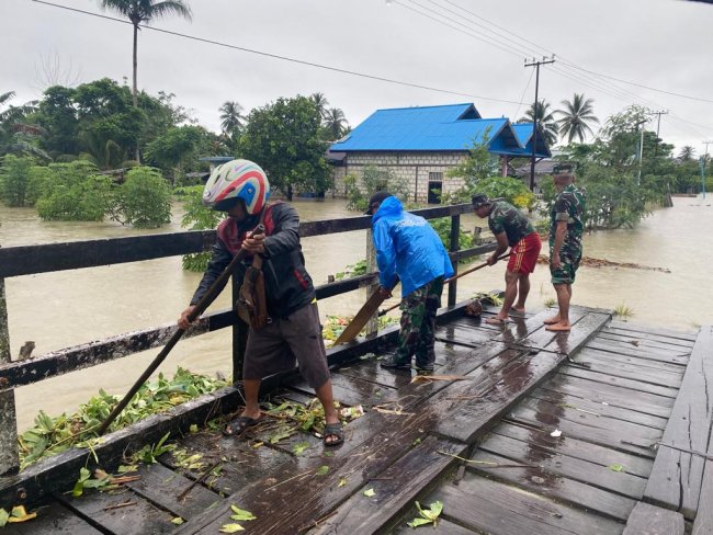 Babinsa Koramil Nimboran Bantu Warga Membersihkan Jalan Akibat Luapan Banjir 